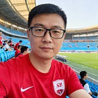 一位戴眼镜的中国男性球迷头像照片，穿着红色球迷T恤，背景是足球场看台。
